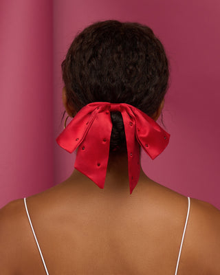 Kitsch Holiday Satin & Rhinestone Bow Scrunchie
Person with a red bow in their hair against a pink background