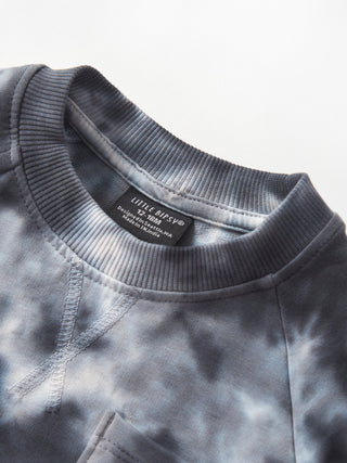 Little Bipsy Marble Pullover - Blue
Close-up of a gray tie-dye sweatshirt with a brand label on a light gray background