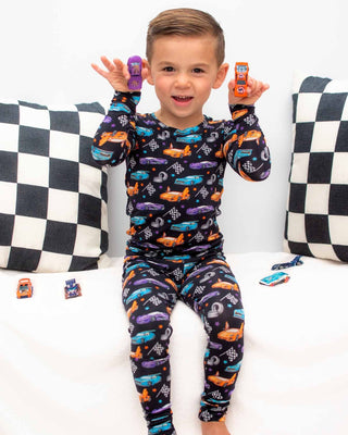 Lev Baby Pajama Set - Elias
Child wearing car-themed pajamas with checkered pillows in the background