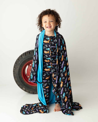 Lev Baby Poppy Convertible Zipper Romper - Elias
Child wearing a colorful blanket with car pattern on a white background