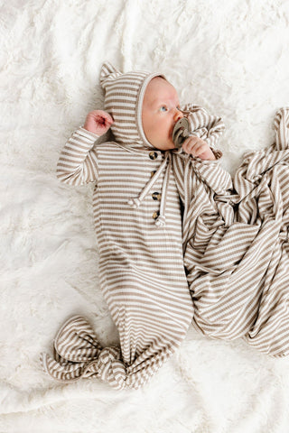 Lou Lou and Company Ribbed Knotted Gown - Indy
Newborn baby in a striped outfit lying on a white blanket