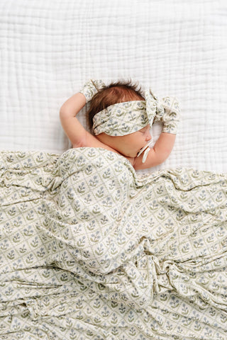 Lou Lou and Company Swaddle Blanket - Etta
Baby wrapped in a floral blanket with a matching headband on a white textured surface