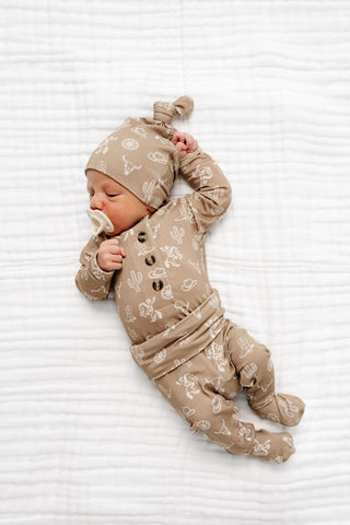 Lou Lou and Company Top and Bottoms - Wyatt
Newborn baby in a beige outfit with patterns on a white textured surface