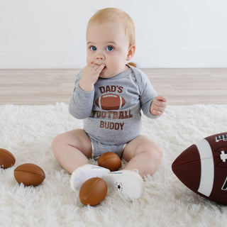 Sweet Wink Dad's Football Buddy Long Sleeve Bodysuit - Gray Baby wearing a 'Dad's Football Buddy' onesie sitting on a white rug with football-themed items.