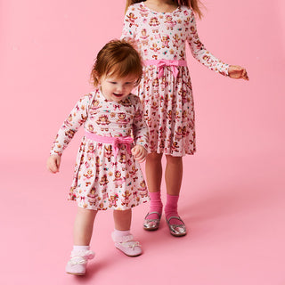 Posh Peanut Bow Twirl Bodysuit Dress- Ginger Posh
Two children in matching floral dresses with pink ribbons on a pink background