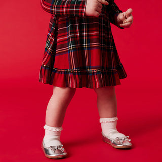 Posh Peanut Ruffled Bodysuit Dress - Red Tartan Plaid
Child wearing a red plaid skirt with white shoes on a red background