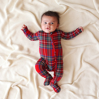 Posh Peanut Footie Zippered One Piece - Red Tartan Plaid
Baby wearing a red plaid onesie lying on a beige blanket