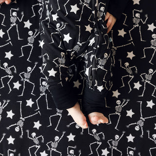Posh Peanut Funny Bones Glow in the Dark Convertible One Piece
Baby in a black outfit with skeleton and star pattern on a matching background