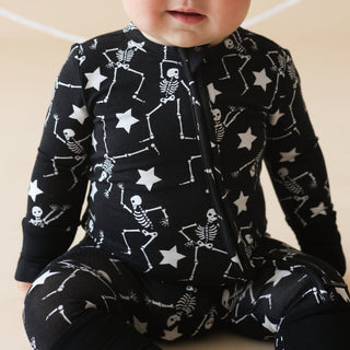 Posh Peanut Funny Bones Glow in the Dark Convertible One Piece
Baby wearing a black onesie with skeleton and star pattern on a beige background