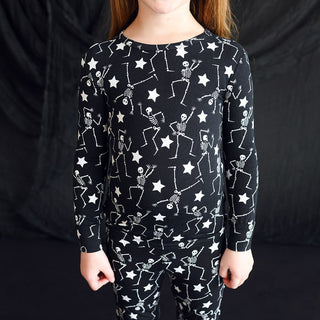 Posh Peanut Funny Bones Glow in the Dark Classic Pajama Set
Child wearing a black long-sleeve shirt with skeleton and star pattern against a black background