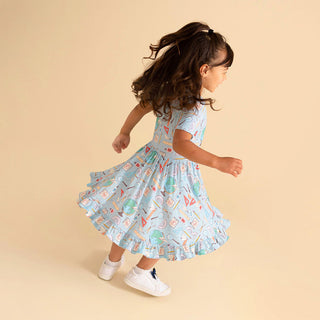 Posh Peanut Steve Ruffled Twirl Dress Child wearing a patterned dress on a beige background