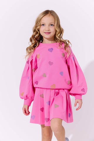 Lola and The Boys Hot Pink Sparkle Hearts Skirt Set
Young girl wearing a pink outfit with heart patterns on a white background