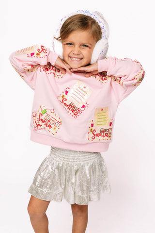 Princess of Sparkles Queen of Sparkles KIDS Letters to Santa - Pink 
Child wearing a pink sweatshirt with text and graphics, white shorts, and white ear muffs on a white background
