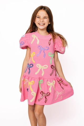 Princess of Sparkles Queen of Sparkles KIDS Sequin Multi Bow With Poof Sleeve Dress
Young girl wearing a pink dress with colorful bow patterns on a white background