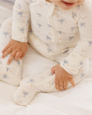 Quincy Mae Bamboo Zip Footie - Hanukkah
Baby in a white onesie with blue floral patterns on a white background