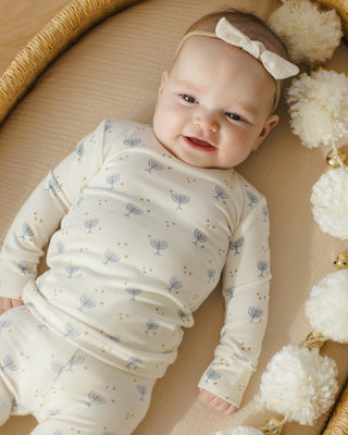 Quincy Mae Bamboo Pajama Set - Hanukkah
Baby in a white outfit with blue patterns lying on a beige surface surrounded by decorative elements.