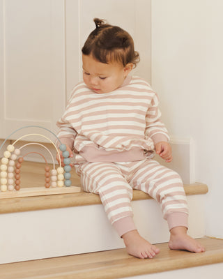Quincy Mae Relaxed Sweatshirt & Relaxed Sweatpant Set - Pink Stripe
Child in striped pajamas sitting on a wooden step with a wooden toy.