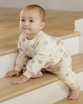 Quincy Mae Relaxed Sweatshirt & Relaxed Sweatpant Set - Brown Bear Baby in a beige outfit with floral patterns sitting on wooden stairs.