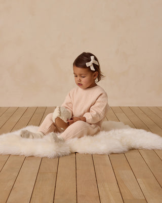 Quincy Mae Textured Sweat Set - Antique
Child sitting on a white fur rug in a room with wooden floor and beige walls