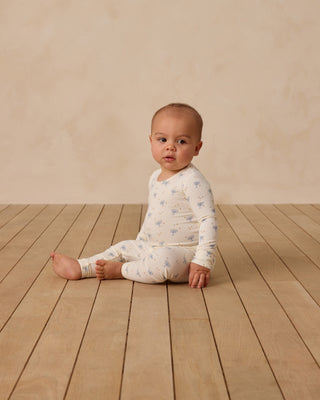 Quincy Mae Bamboo Pajama Set - Hanukkah
Baby sitting on a wooden floor wearing a white onesie with blue patterns.