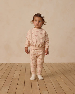 Quincy Mae Relaxed Fleece Sweatshirt & Sweatpant Set - Red Bows
Child wearing a pink outfit with bow patterns on a wooden floor and beige wall background