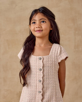 Noralee Gabrielle Dress - Rose
Young girl wearing a beige dress with buttons against a beige background