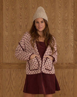 Rylee & Cru Womens Quilted Jacket - Blush Fleur Woman wearing a patterned cardigan and maroon dress against a wooden paneled wall.