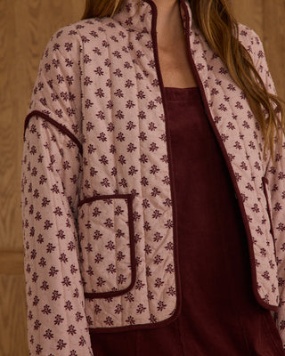 Rylee & Cru Womens Quilted Jacket - Blush Fleur Person wearing a patterned quilted jacket over a maroon outfit against a beige background