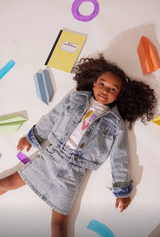 Lola and The Boys Rainbow Sparkle Denim Skirt
Child wearing a denim jacket with colorful letters and shapes on a white background