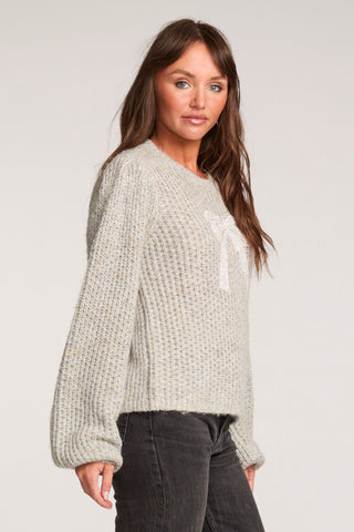 Saltwater Luxe Long Sleeve Bow Sweater in Heather Grey
Woman wearing a chunky knit sweater and dark jeans on a plain background