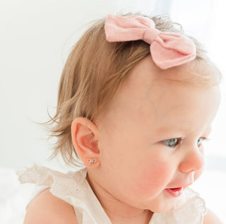 Cherished Moments Sterling Silver Bow Earrings with Pink CZs with Screw Backs Baby with a pink bow in hair and matching earring on a light background