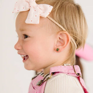 Pierced Co. Cactus
Profile of a young girl wearing a pink headband with a bow, smiling.