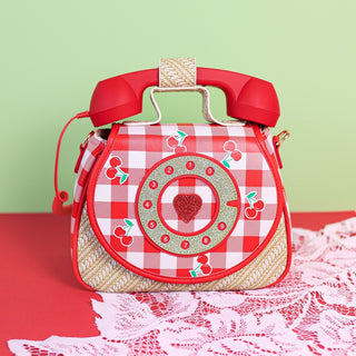 Ring Ring Phone Convertible Handbag - Cherry Red and white checkered bag with a telephone design on a red surface with a green background