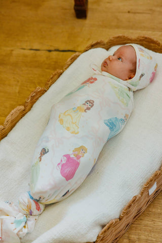 Copper Pearl Disney Princess Knit Swaddle Blanket
Newborn baby swaddled in a blanket with princess designs on a wooden floor.