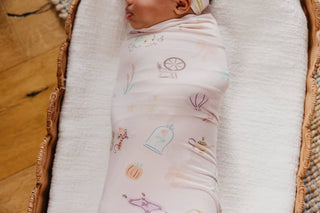Copper Pearl Disney Enchanted Friends Knit Swaddle Blanket
Baby swaddled in a patterned blanket lying on a wooden floor.