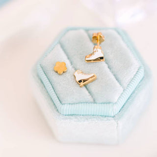 Pierced Co. Ice Skates Earrings 
Gold ice skate earrings on a light blue hexagonal jewelry cushion.