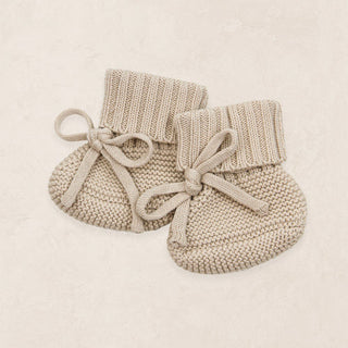 Lou Lou and Company Knit Booties - Tan
Pair of beige knitted baby booties with drawstrings on a light beige background