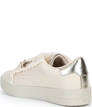 Steve Madden Kid's Emora Sneaker - Cream
A low-top sneaker in off-white leather with a metallic silver heel tab, a gold star charm detail on the side, and a white lace with ruffles. The shoe is photographed from a three-quarters angle against a clean white background.