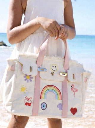 Lola and The Boys Beachkin Bag
Person holding a colorful tote bag with cartoon designs on a beach.