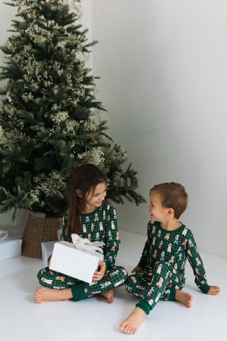 In My Jammers Christmas Pups Two Piece Set
Two children in matching green pajamas sitting on the floor next to a decorated Christmas tree.