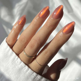 Glamnetic Press-On Nails Short Almond - Rosé
Hand with long, glittery orange nails wearing a gold ring on a white background