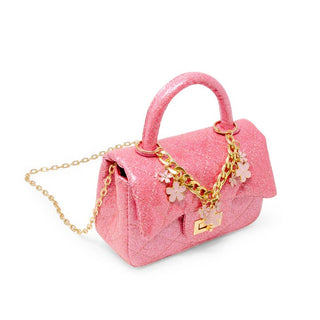 Pink glittery handbag with gold chain and floral charms on a white background