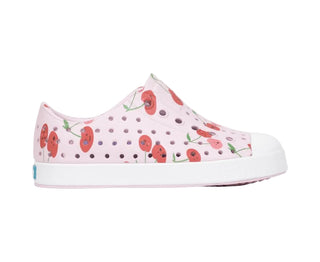 Native Jefferson Print Shoes - Barely Pink / Shell White / Cherries
A pink slip-on shoe with a perforated upper, decorated with a red poppy floral pattern, and a white rubber toe cap and sole, shown against a light gray background.