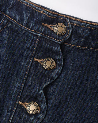 Rylee & Cru Scallop Mini Skirt - Dark Indigo
Close-up of dark indigo denim fabric with three brass buttons and contrast tan stitching, showing the button details and denim texture.