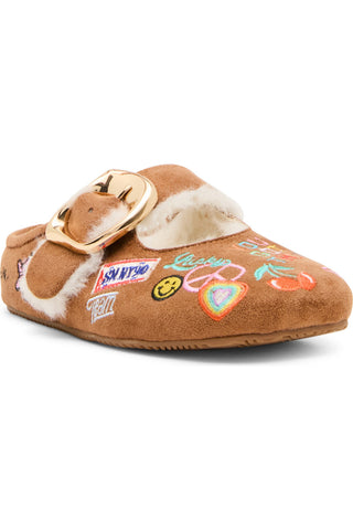 Steve Madden Kid's Faux Fur Nugget - Cognac Multi
A brown suede mule slipper decorated with colorful embroidered patches, a white faux-fur trim, and a large gold buckle on the strap, shown against a plain white background.