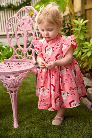 Pink Chicken Baby Girls Jennifer Dress Set - Pink Candy Cane Santa
Child in a pink dress standing next to a pink chair outdoors