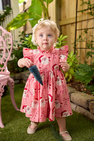 Pink Chicken Baby Girls Jennifer Dress Set - Pink Candy Cane Santa
Young girl in a pink dress with floral patterns holding a blue toy outdoors.