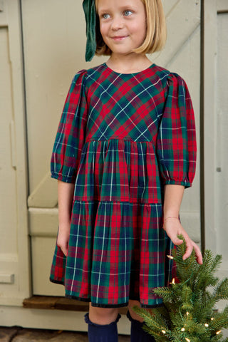 Pink Chicken Girls Maribelle Dress - Red Tartan
Young girl wearing a red and green plaid dress standing next to a Christmas tree.