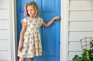 Pink Chicken Girls Adaline Dress - Colorful Menorahs
Young girl in a patterned dress standing in front of a blue door.