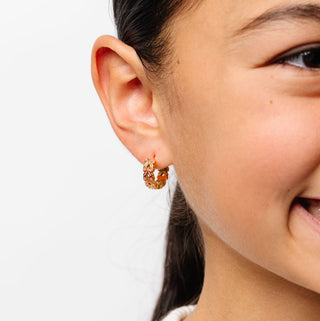 Pip Pop Post Earrings - Bow Repeat Hoop
Close-up of a person wearing gold hoop earrings with a plain background